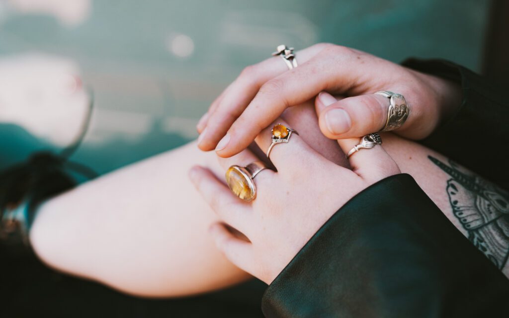 Close-up branding image showing relaxed hands on a tattooed thigh with soft green tones, part of a stylized personal portrait session.